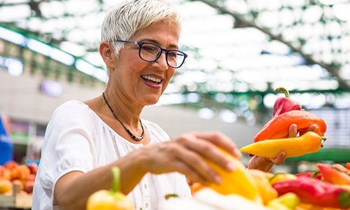 a woman smiling and holding a bunch of vegetables