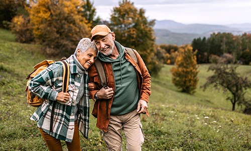 a man and woman standing in a field with trees and grass