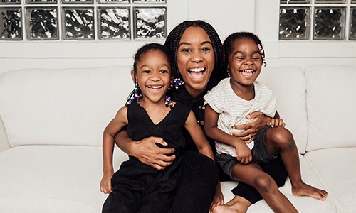 a woman sitting on a couch with two kids