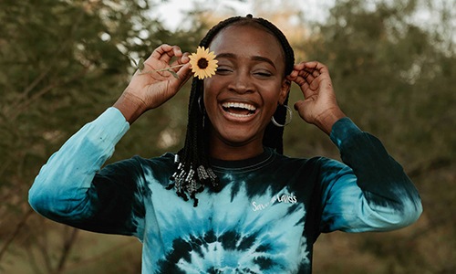 woman holds a flower in her hair in a park